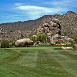 A golf course with a large rock formation in the background.